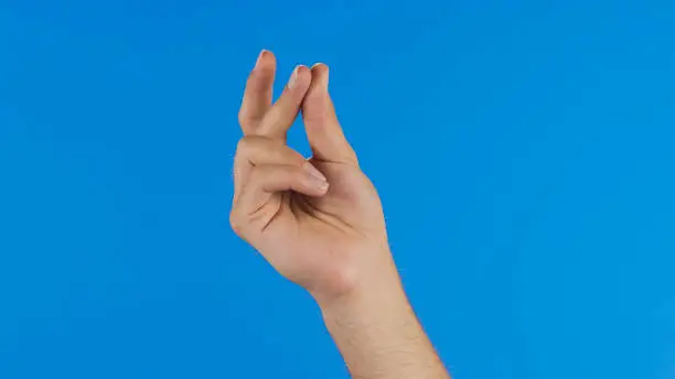 Female hand with snapping fingers on blue screen background.