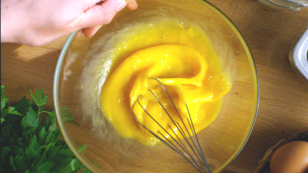 istock Woman whisking eggs. Whipped eggs in glass bowl with broken empty egg shell. 1370738823