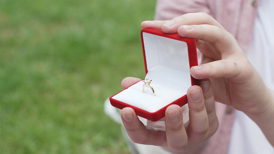 Man holding box with ring making propose to his girlfriend.