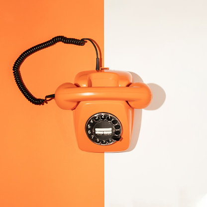 Creative layout with retro orange phone on white and bright orange background. Happy life idea with telephone. Spring or summer minimal trendy concept with hand set. Flat lay.