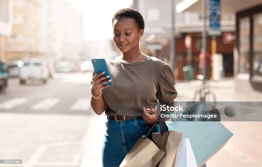 Shot of an attractive young woman using her cellphone  outside while shopping in the city On to the next Shopping Stock Photo