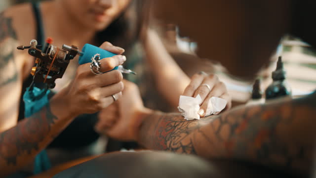 Woman tattoo artist doing tattoos for her boyfriend.