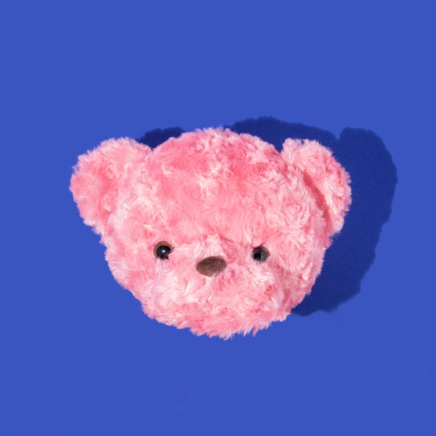 Creative layout with pastel pink teddy bear head on deep blue background. Aesthetic fashion concept with toy. Colorful minimal  trendy idea.