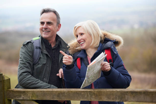 istock Mature Retired Couple Walk In Fall Or Winter Countryside Standing By Gate Looking At Map 1370743789