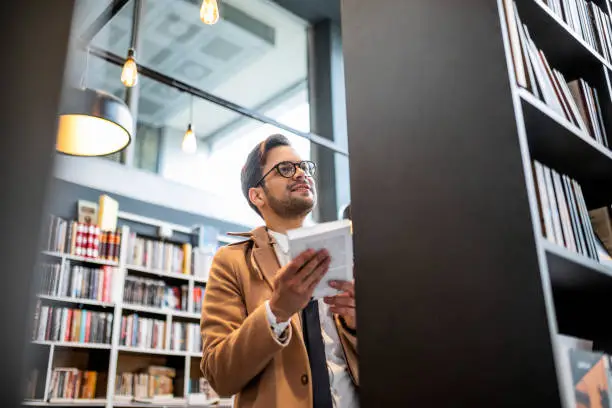 Young businessman in library ,bookstore looking for book