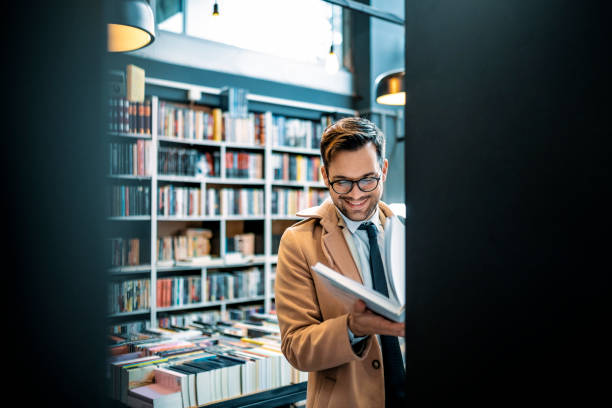 młody biznesmen w bibliotece, księgarni szuka książki - book holding necktie businessman zdjęcia i obrazy z banku zdjęć