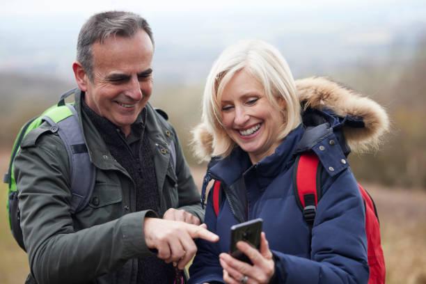 istock Mature Retired Couple Walk In Fall Or Winter Countryside Using Map Or Navigation App On Mobile Phone 1370743856