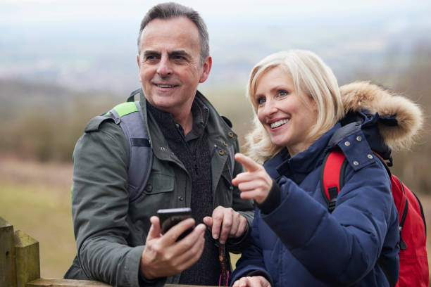 istock Mature Retired Couple Walk In Fall Or Winter Countryside Using Map Or Navigation App On Mobile Phone 1370743857