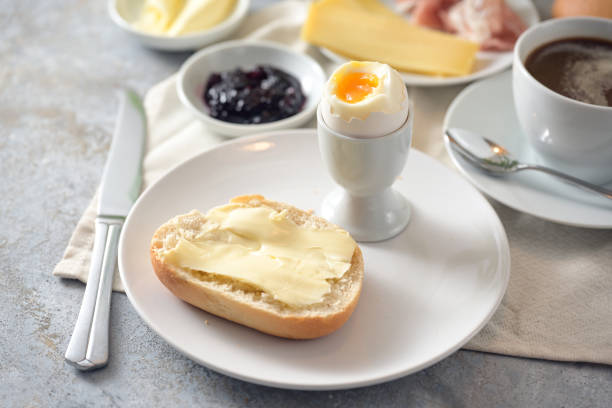 istock Bread roll with butter, cooked egg, jam and coffee on a breakfast table, selected focus 1370745234