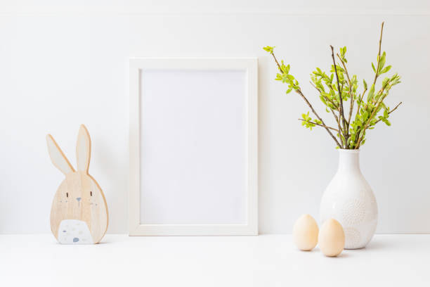 istock Home interior with easter decor. Mockup with a white frame and willow branches in a vase, easter eggs on a light background 1370748361