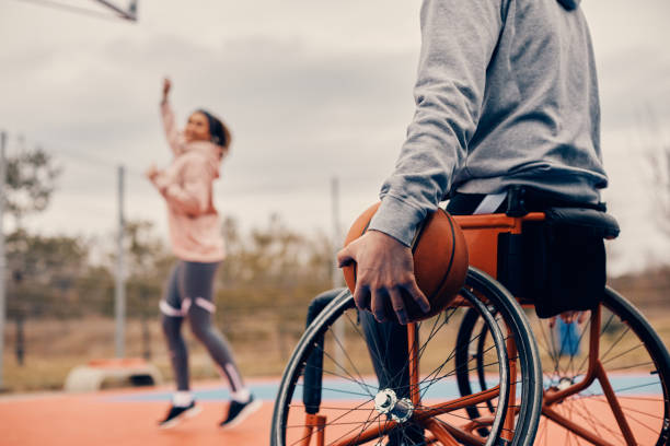 atleta irriconoscibile in carrozzina che tiene il basket sul campo sportivo all'aperto. - basket su sedia a rotelle foto e immagini stock