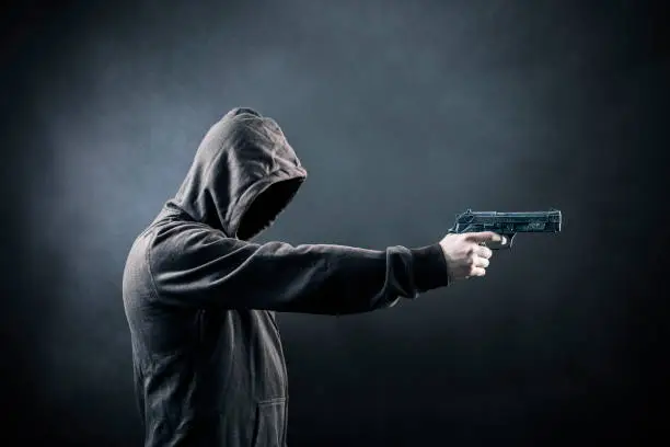 Hooded man with a gun in the dark