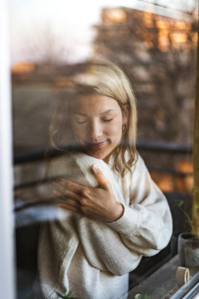 Smiling loving young woman hugging oneself