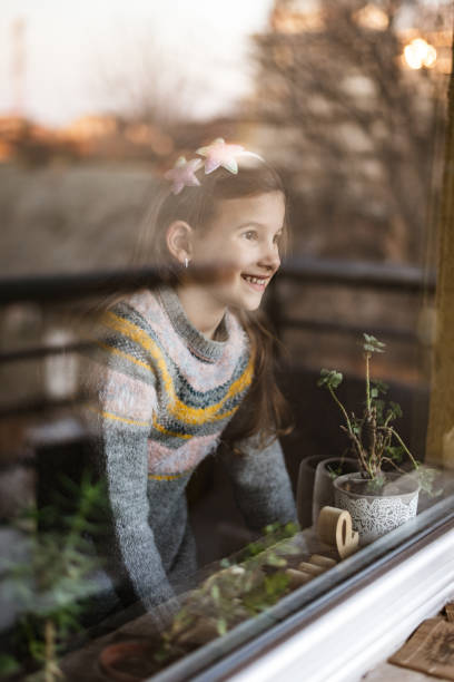 istock Smiling loving young girl looking through a window 1370753740