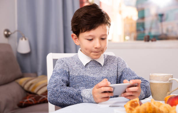 istock Teenager plays on smartphone in kitchen interior 1370754178