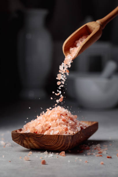 pink salt is poured into a small wooden bowl. - pink salt imagens e fotografias de stock