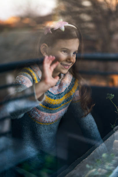 istock Smiling loving young girl looking through a window 1370754681