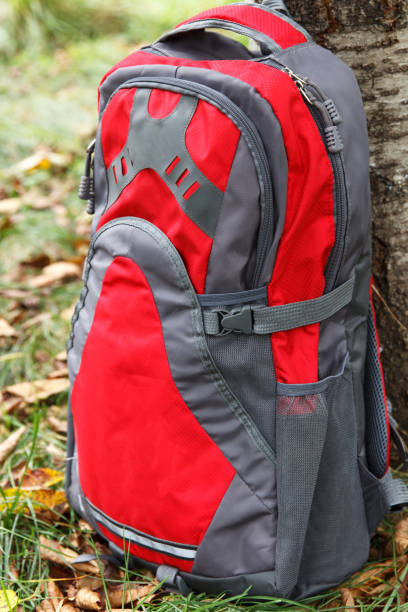 istock Convenient and high-quality camping backpack, red - gray color set near a tree at a camping 1370757809