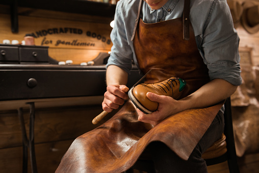 Cropped picture of young shoemaker in workshop making shoes.