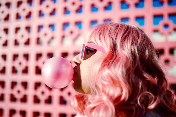 Pink Haired Woman Blowing Gum Bubble stock photo