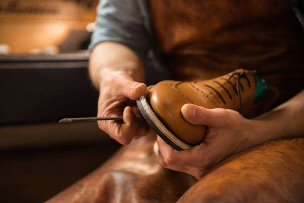 Shoemaker in workshop making shoes. stock photo