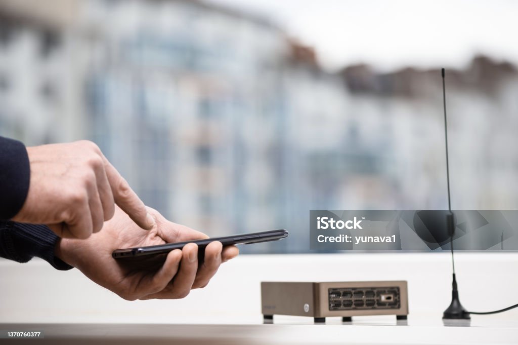 Wireless hotspot for helium token mining. A man with a smartphone is setting up a wireless hotspot for Helium token mining. Cryptocurrency Stock Photo