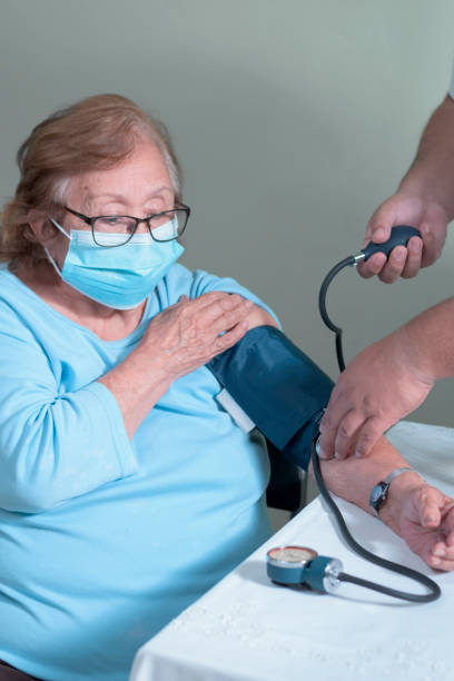 older adult latin woman in a test to measure her blood pressure as a prevention measure stock photo