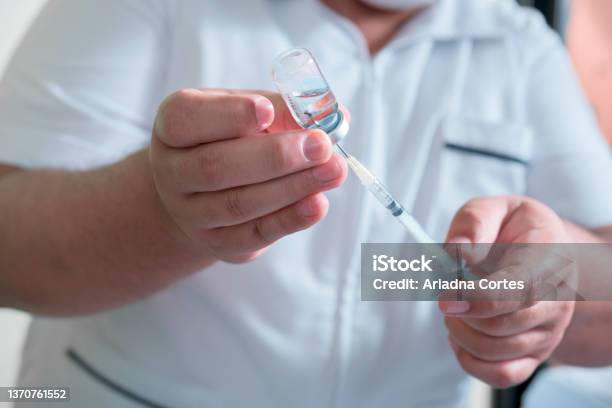 Closeup To The Hands Of A Latin Man Holding A Syringe And Medicinal Liquid To Be Injected As A Vaccine Stock Photo - Download Image Now