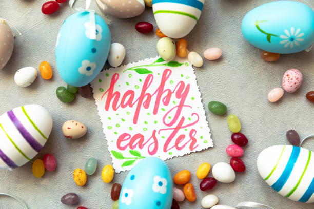 Happy Easter concept. Preparation for holiday. Easter eggs Inscription HAPPY EASTER letters candy chocolate eggs and jellybean sweets on concrete stone grey background. Flat lay top view copy space