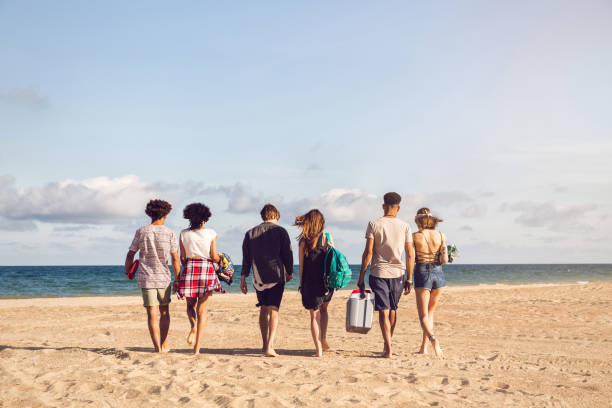 istock Young people walking on the beach carrying a cooler box 1370764137