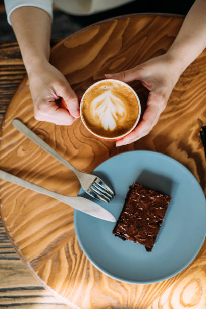 tendo uma pequena pausa com uma xícara de café com leite e brownie de chocolate branco - molécula de cafeína - fotografias e filmes do acervo