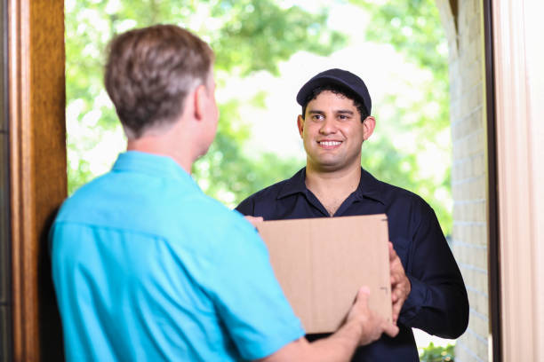istock Latin descent delivery man with box arrives at customer home. 1370765473