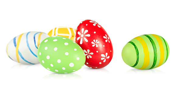 Dyed handmade Easter eggs in a row on green colored background