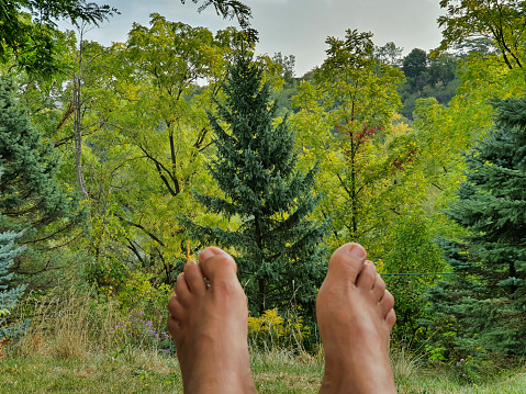 Lying feet of a woman relaxing with a view of the forest.