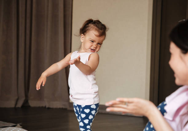 Image of pretty young mother talking with her little daughter indoors. Looking aside.