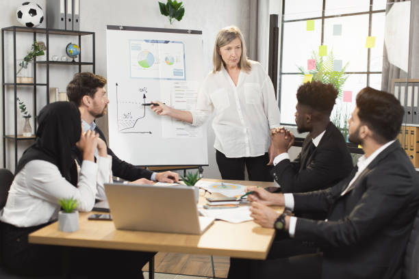 istock Aged woman leading conference for diverse compaby workers 1370766953