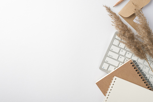 Top view photo of workspace keyboard notebooks pencil envelope card and pampas grass on isolated white background with copyspace