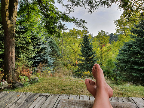 Lying feet and legs of a woman relaxing with a view of the forest.
