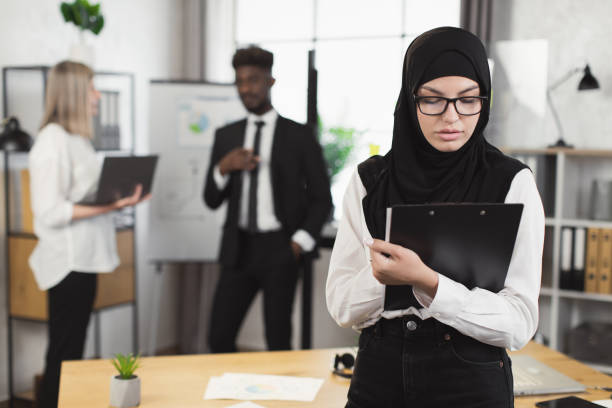 istock Woman in hijab using clipboard with colleagues at office 1370768749
