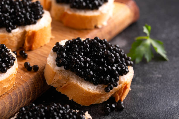tranches de pain au caviar noir sur fond sombre rustique - caviar photos et images de collection