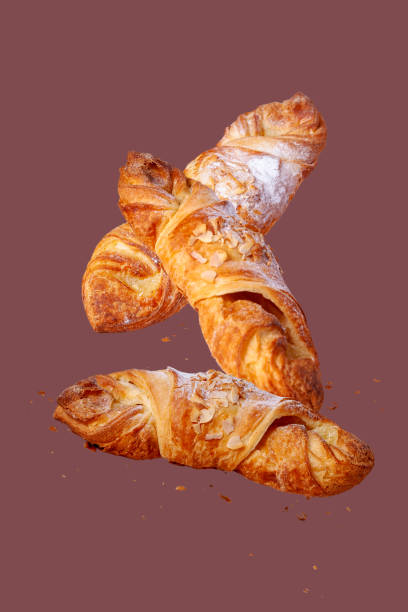 istock croissants with almonds fly on a burgundy background 1370775397