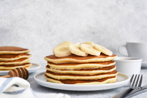 istock Stack of honey and banana pancakes on the kitchen table for breakfast. 1370775829