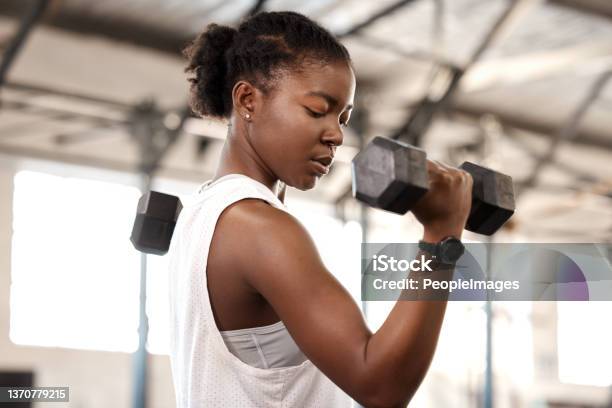 Shot Of A Sporty Young Woman Exercising With A Dumbbell In A Gym Stock Photo - Download Image Now