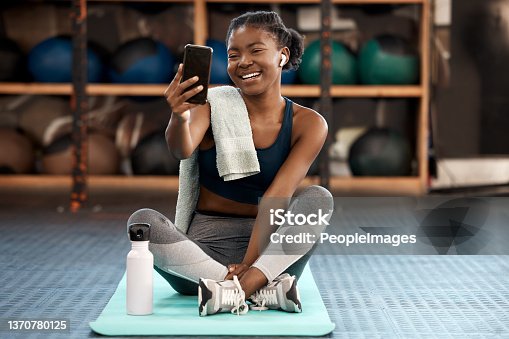istock Shot of a sporty young woman taking selfies while exercising in a gym 1370780125