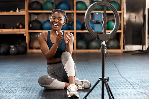 Shot of a sporty young woman recording herself while exercising in a gym
