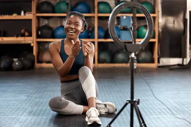 Photo of Shot of a sporty young woman recording herself while exercising in a gym