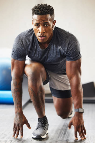 shot of a muscular young man exercising in a gym - twenty first imagens e fotografias de stock