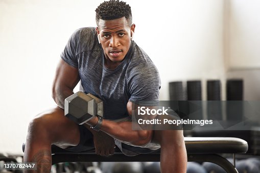 istock Portrait of a muscular young man exercising with a dumbbell in a gym 1370782447