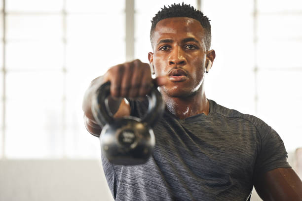 Shot of a muscular young man exercising with a kettlebell in a gym Visualise the goal, then go for it gym men africa muscular build stock pictures, royalty-free photos & images