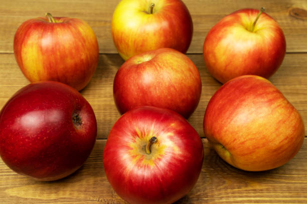 istock Red ripe apples on wooden table, close up. 1370784414